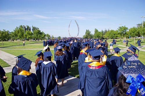 Graduates walking through beginnings sculpture