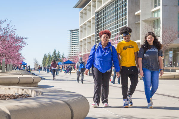 Students having a conversation, laughing and walking across campus