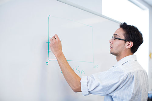A student drawing a graph on a whiteboard